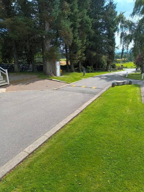 an empty road with a grass median in a park at Lynmar retreat No 35 in Dornoch