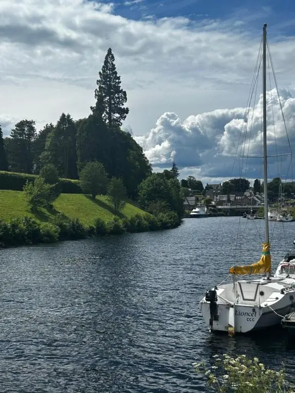 a boat sitting in the water on a river at Aldernaig Mill in Invergarry