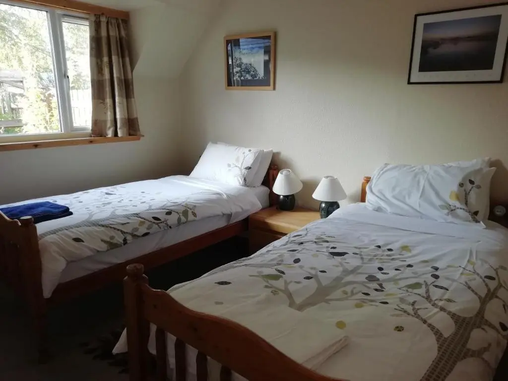 a bedroom with two beds and a window at Fraoch Lodge in Boat of Garten