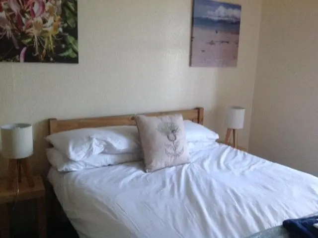 a bed with white sheets and pillows on it at Fraoch Lodge in Boat of Garten