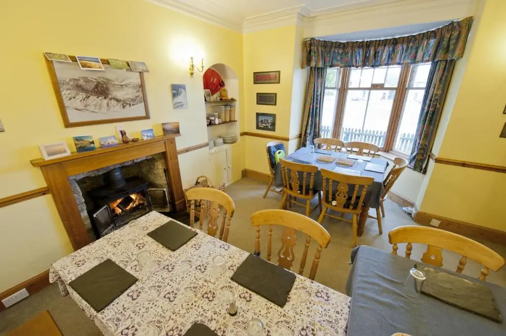 a dining room with a table and a fireplace at Fraoch Lodge in Boat of Garten