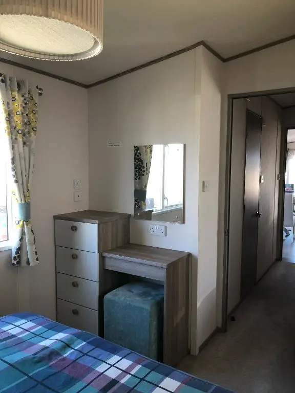 a bedroom with a bed and a dresser and a mirror at Ballies Retreat in Lossiemouth