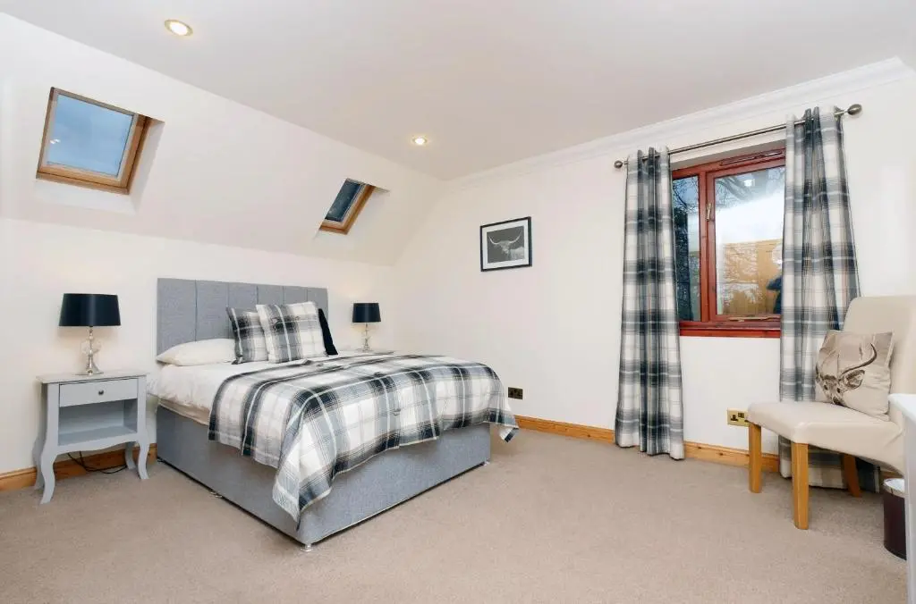 a bedroom with a bed and a chair and a window at Culliss House B&B in Inverness