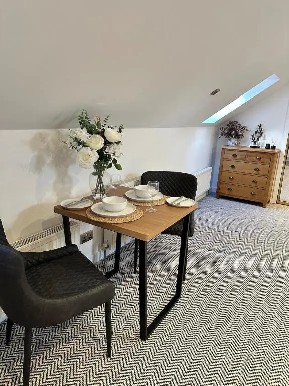 a room with a table with a vase of flowers on it at An Cuiltheann Apartment in Turriff
