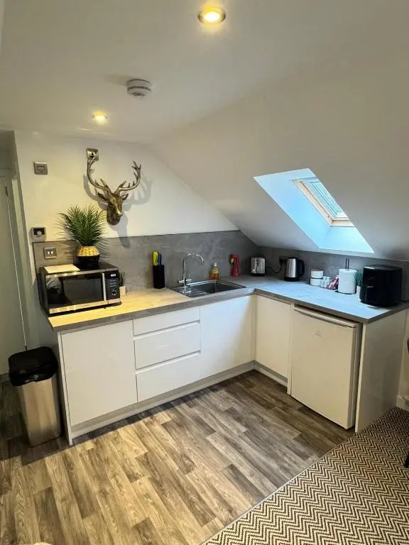 a kitchen with white cabinets and a sink and a window at An Cuiltheann Apartment in Turriff