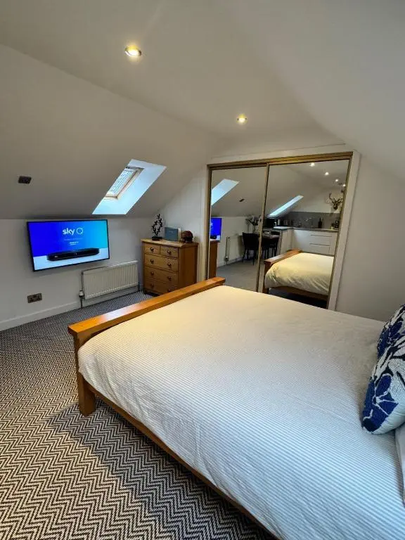 a bedroom with a large bed and a large mirror at An Cuiltheann Apartment in Turriff