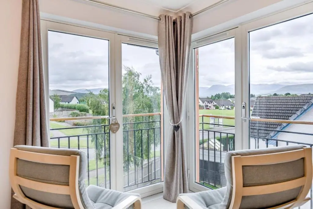 two chairs in front of a balcony with large windows at 2 Bed in Aviemore oc-t30584 in Aviemore