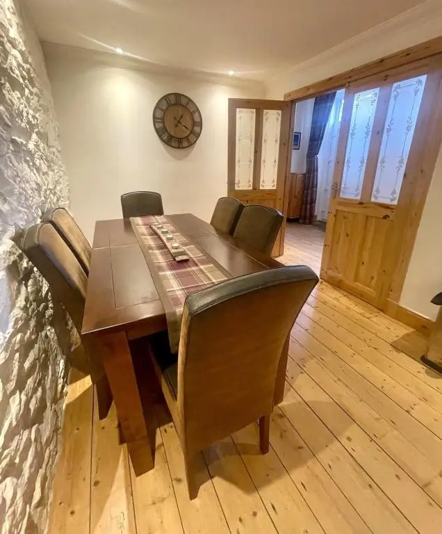 a dining room table with chairs and a clock on the wall at Beautiful 3 bedroom house short walk from the beach in Nairn