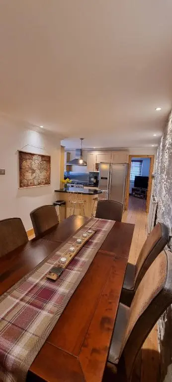 a large wooden table with chairs and a kitchen at Beautiful 3 bedroom house short walk from the beach in Nairn