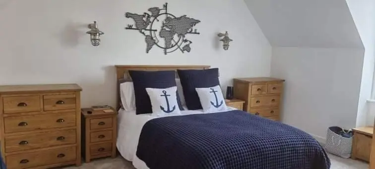 a bedroom with a bed with blue and white sheets and wooden dressers at Beautiful 3 bedroom house short walk from the beach in Nairn
