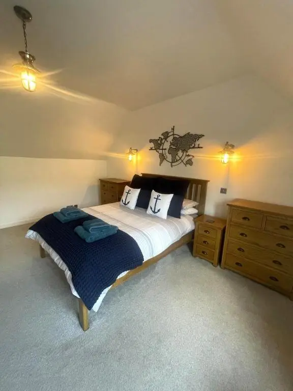 a bedroom with a large bed and two wooden cabinets at Beautiful 3 bedroom house short walk from the beach in Nairn