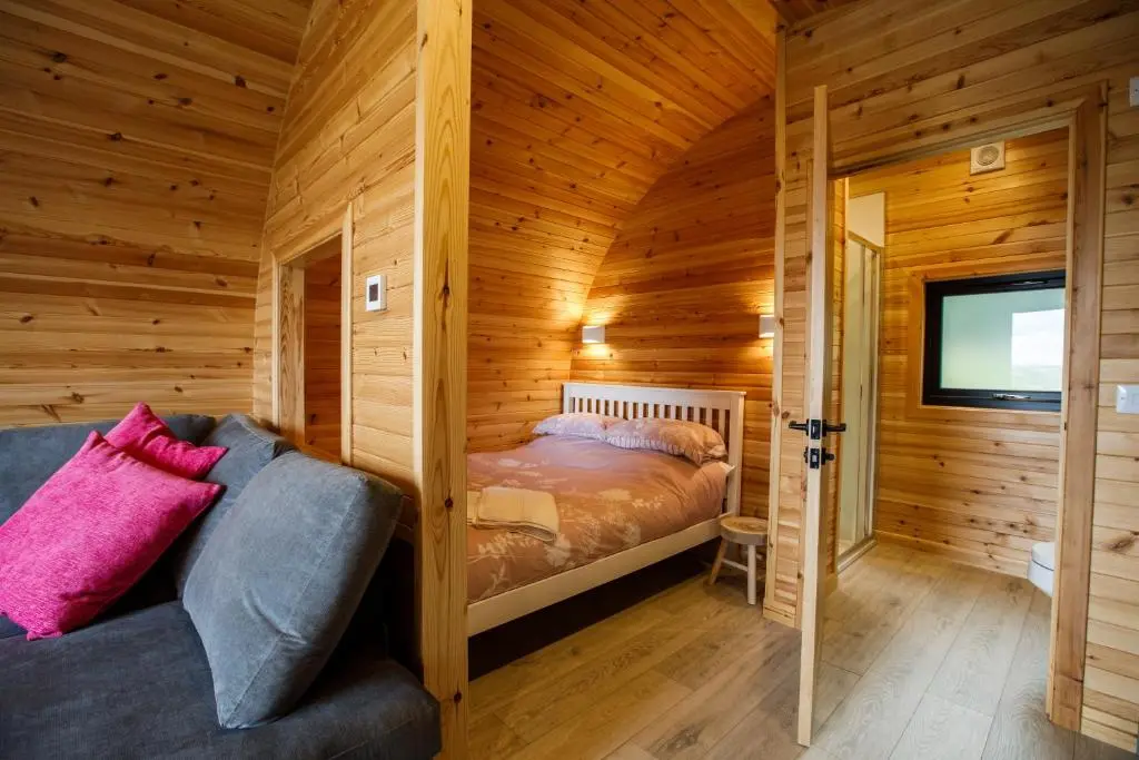a log cabin bedroom with a bed and a tv at Shin View Pods in Lairg