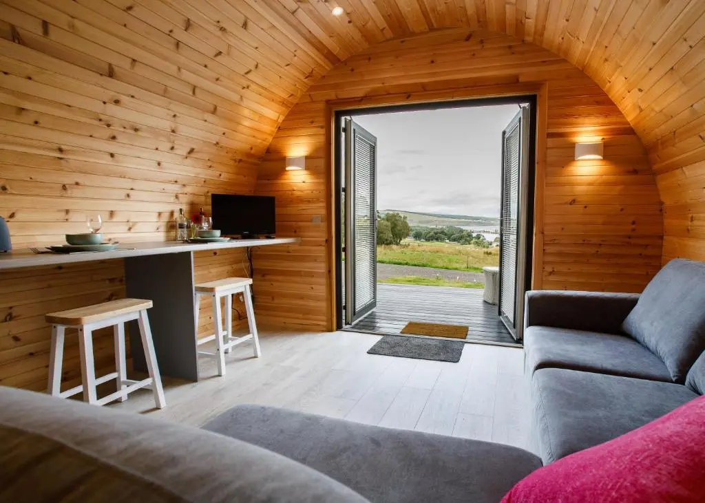 a living room with a couch and a kitchen with a counter at Shin View Pods in Lairg