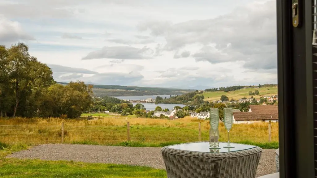 a table with a wine glass sitting on top of a window at Shin View Pods in Lairg
