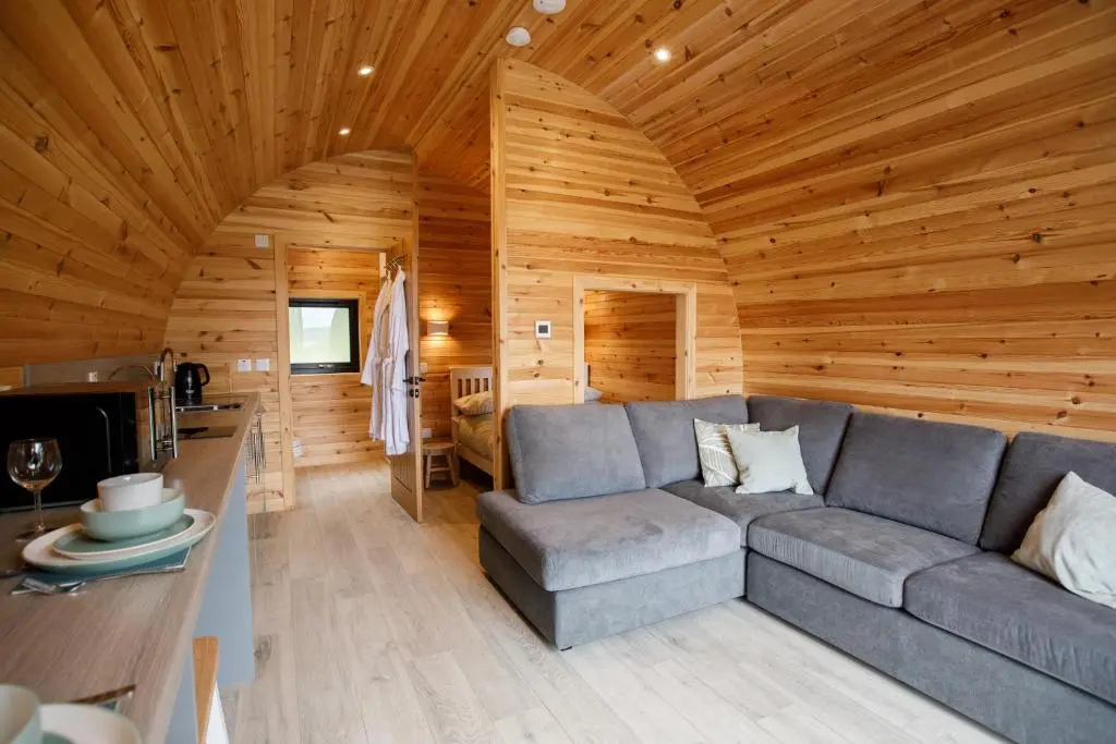 a living room with a gray couch in a wooden cabin at Shin View Pods in Lairg