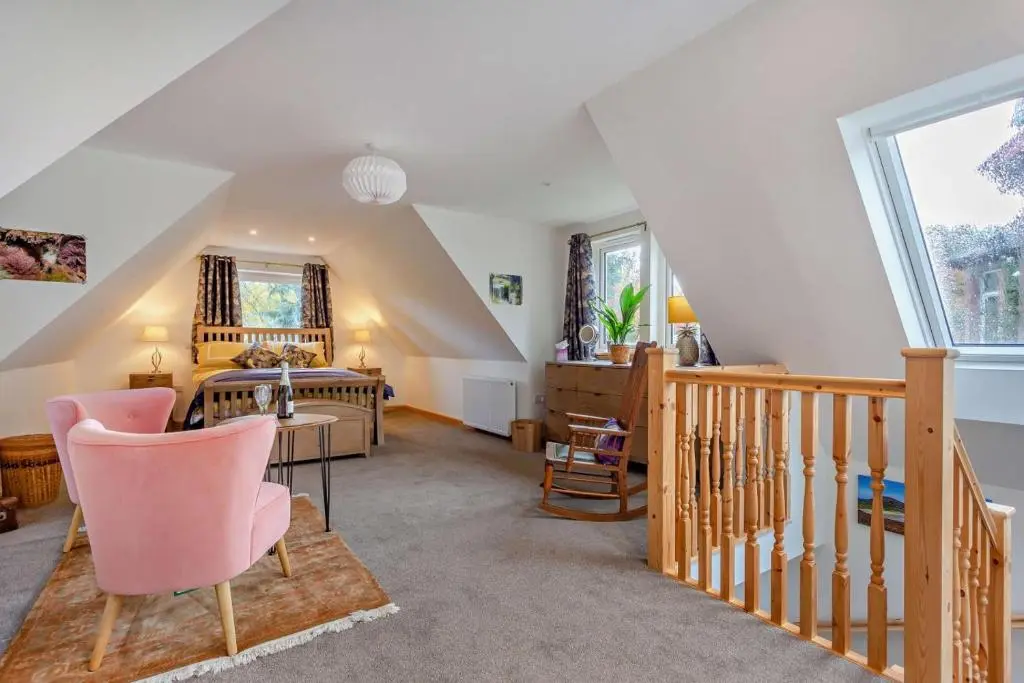 a attic living room with a staircase and pink chairs at 1 Bed in Strathpeffer oc-h30077 in Strathpeffer