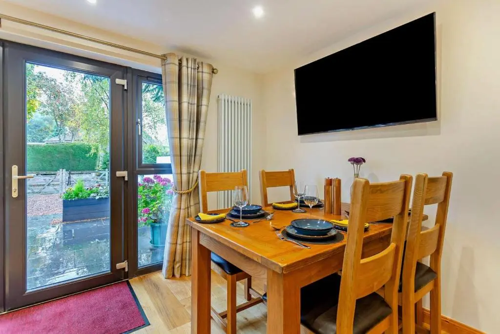 a dining room with a wooden table and a television at 1 Bed in Strathpeffer oc-h30077 in Strathpeffer