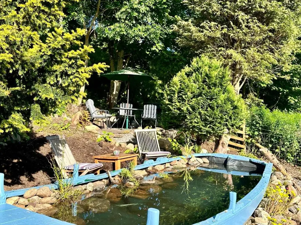 a garden with a pond and two chairs and a table at Beechtree Cottage, Ardle Family Room, Kirkmichael in Kirkmichael