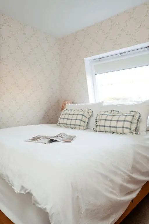 a white bed with two pillows and a window at Park Cottage - Seasgair Lodges in Kingussie