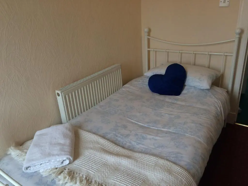 a bed with a blue pillow on top of it at Ardgarry Holiday House in Inverness
