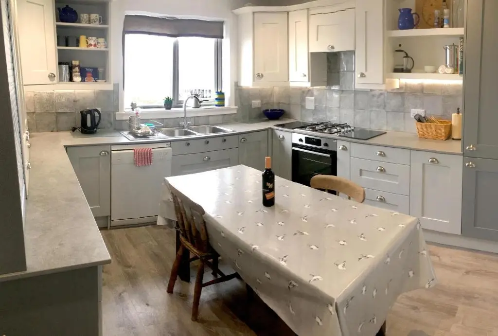 a kitchen with a table with a bottle of wine on it at Bright comfy home, sea views and big skies in Banff