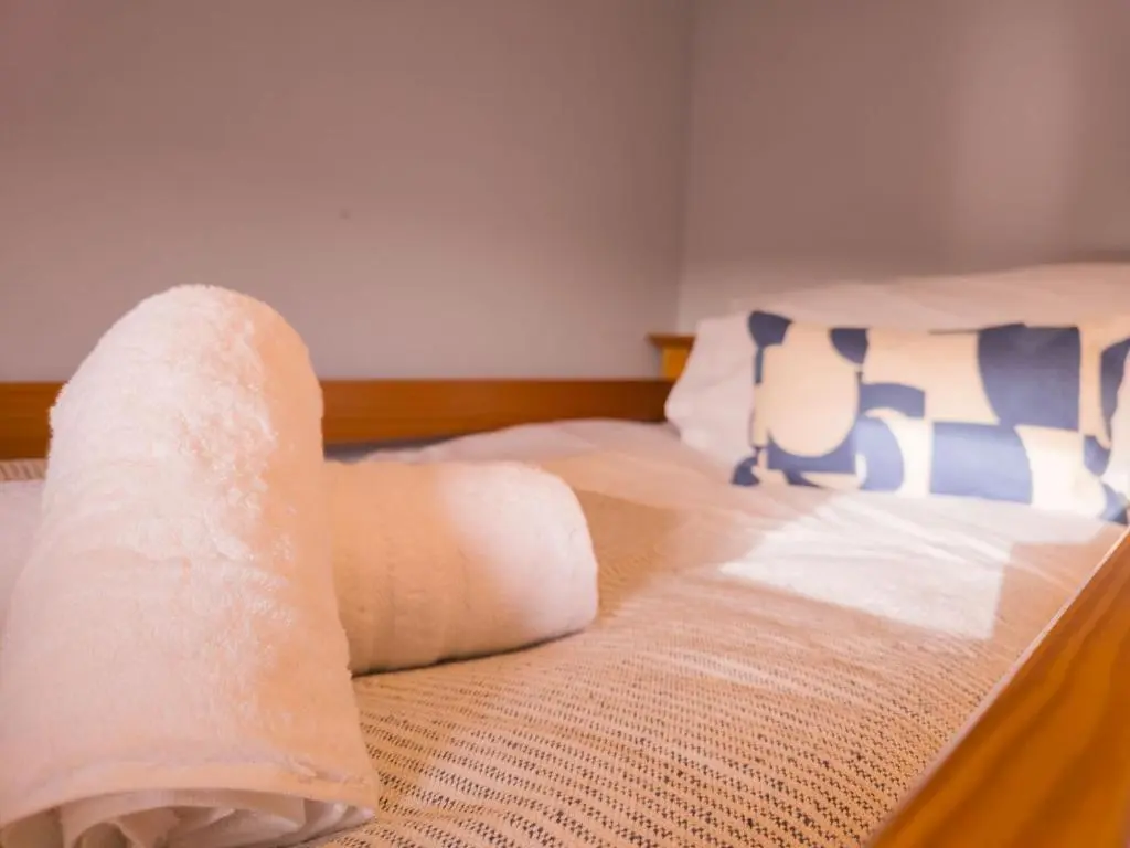 a bedroom with two beds with white sheets and blue pillows at Schoolhouse in Laggan