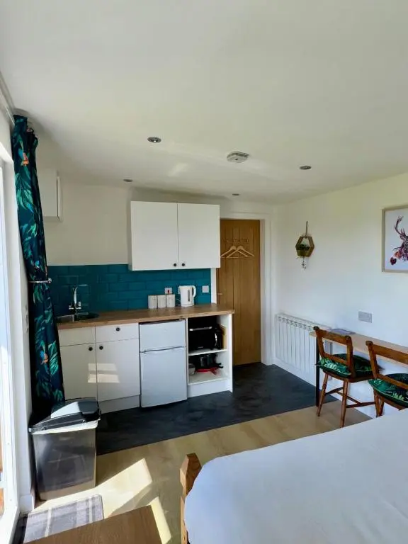 a kitchen with white cabinets and a table at Brae Cabin in Inverness