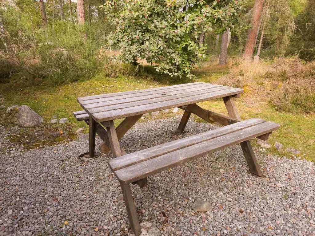 a wooden picnic bench sitting in a park at Taigh Mathair Taigh Mathair in Nethy Bridge