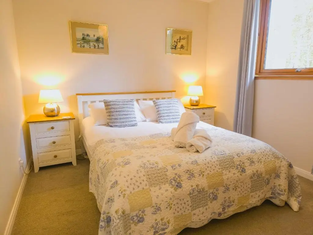 a bedroom with a bed with two night stands and two lamps at Taigh Mathair Taigh Mathair in Nethy Bridge