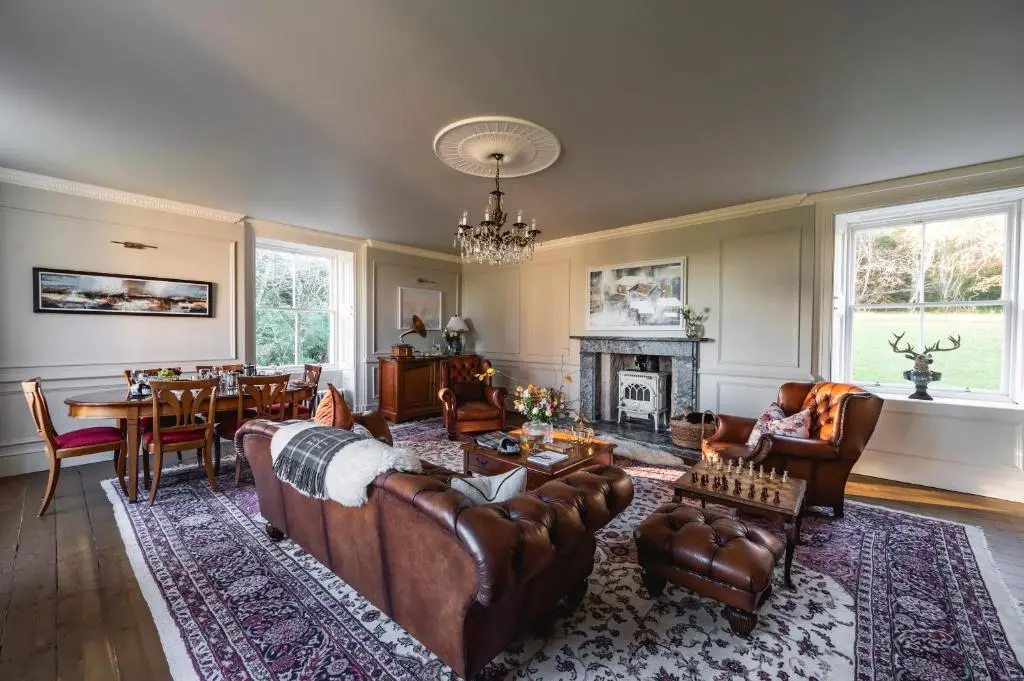 a living room with leather furniture and a fireplace at Burnhervie House in Inverurie