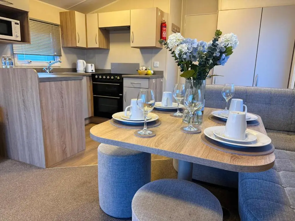 a kitchen with a table with a vase of flowers on it at Little Cha-Am Caravan Hire at Silver Sands in Lossiemouth