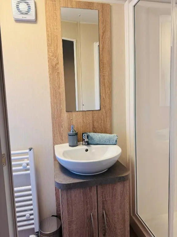 a bathroom with a white sink and a mirror at Little Cha-Am Caravan Hire at Silver Sands in Lossiemouth