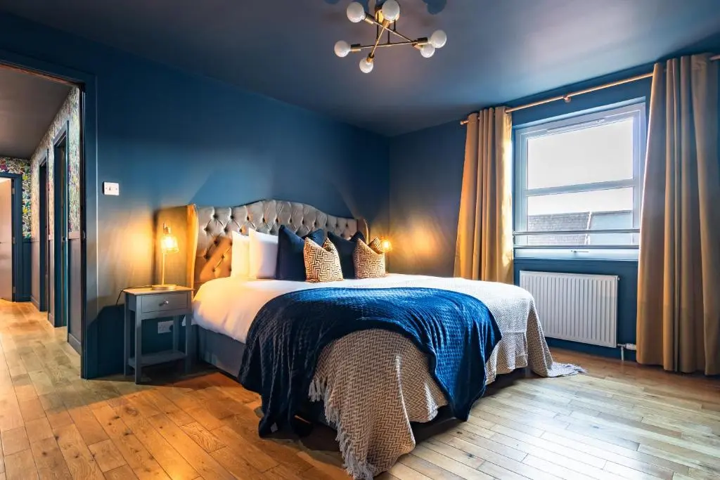 a bedroom with a bed with blue walls and a window at Ness in the City in Inverness