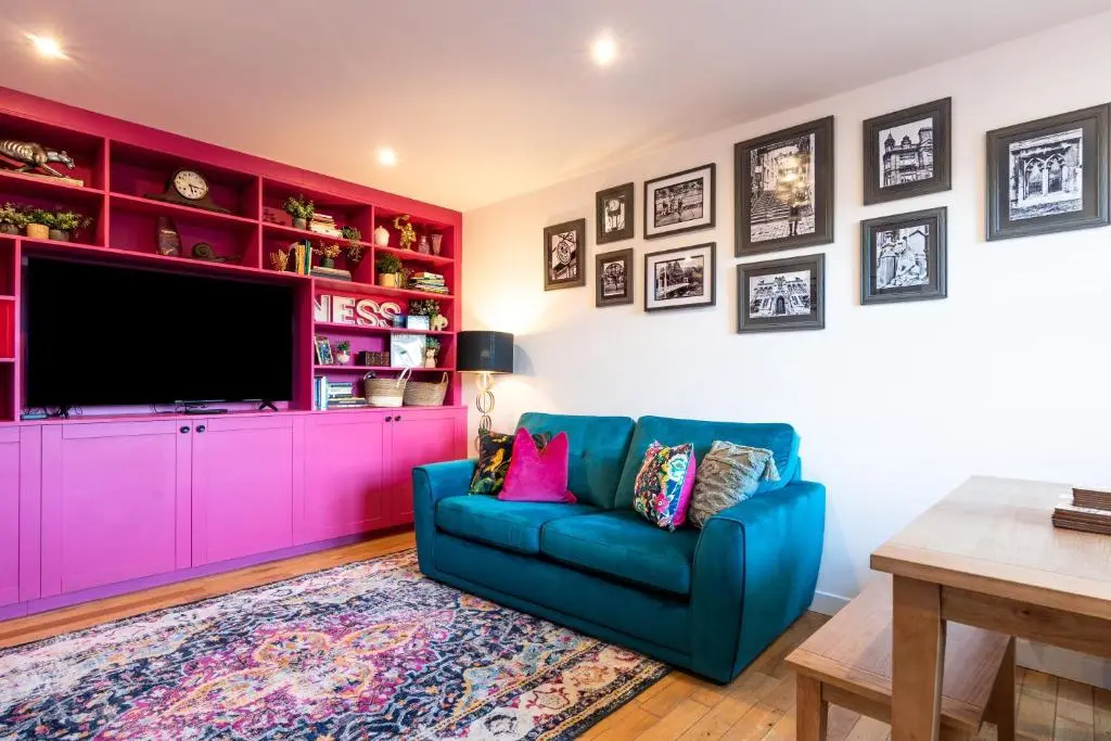 a living room with a blue couch and a pink cabinet at Ness in the City in Inverness