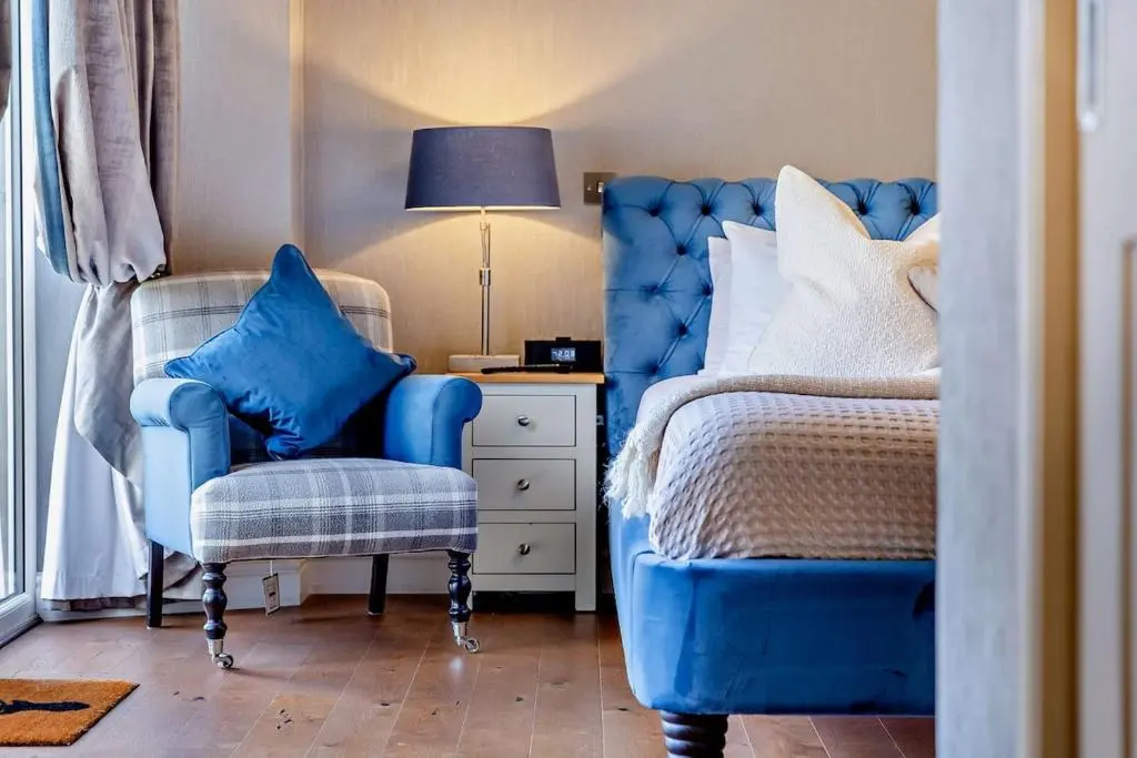 a bedroom with a bed and a chair and a lamp at Glenmore Lodge in Skye of Curr