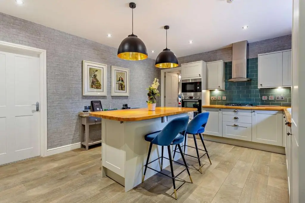a kitchen with a large island with blue bar stools at Glenmore Lodge in Skye of Curr