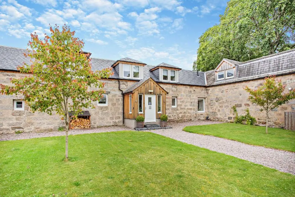 an exterior view of a stone house with a yard at Cairngorm Cottage in Skye of Curr