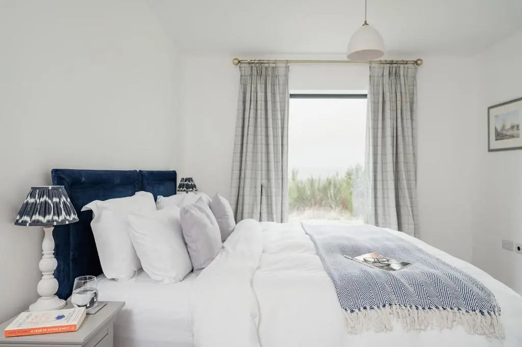 a white bed with white pillows and a window at Osprey's Nest - Seasgair Lodges in Broomhill Station