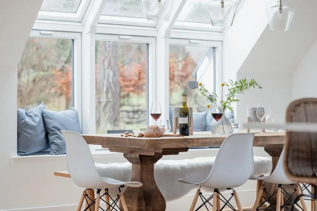 a dining room with a table with two glasses of wine at Osprey's Nest - Seasgair Lodges in Broomhill Station