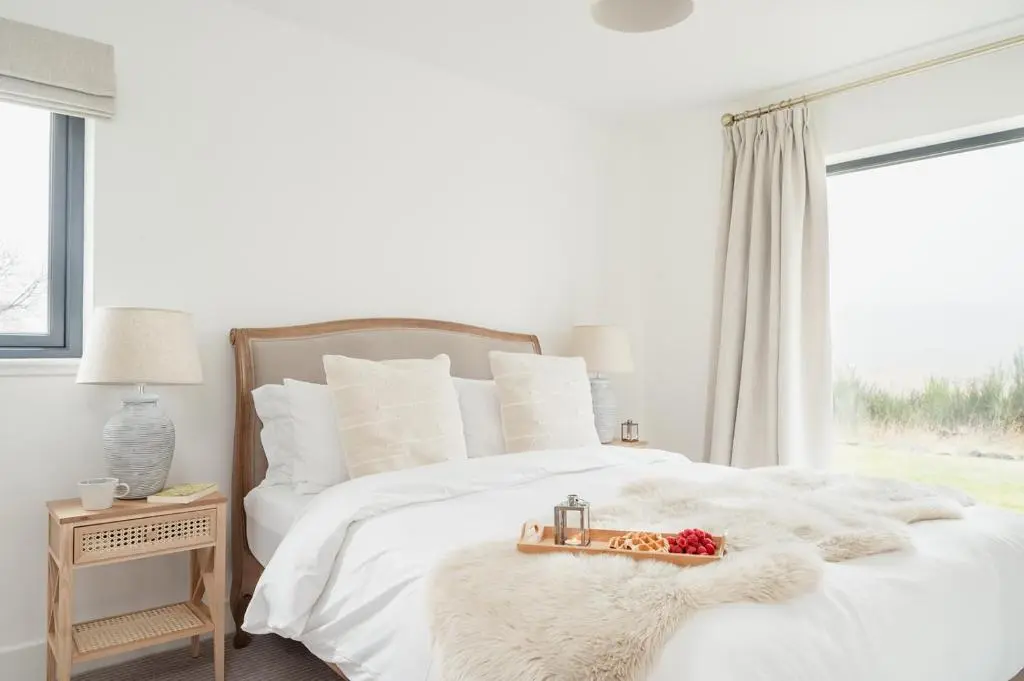 a bedroom with a white bed with a large window at Osprey's Nest - Seasgair Lodges in Broomhill Station