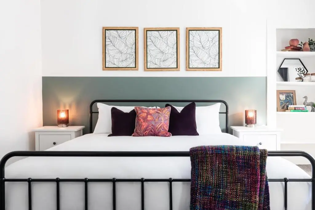 a bedroom with a white bed with three pictures on the wall at Ness Heights, Spacious City Centre Townhouse in Inverness
