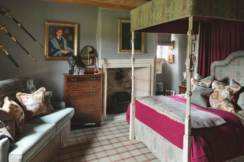 a bedroom with a canopy bed and a fireplace at Forter Castle in Blairgowrie
