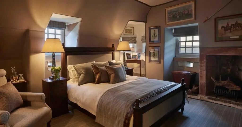 a bedroom with a large bed and a fireplace at Forter Castle in Blairgowrie