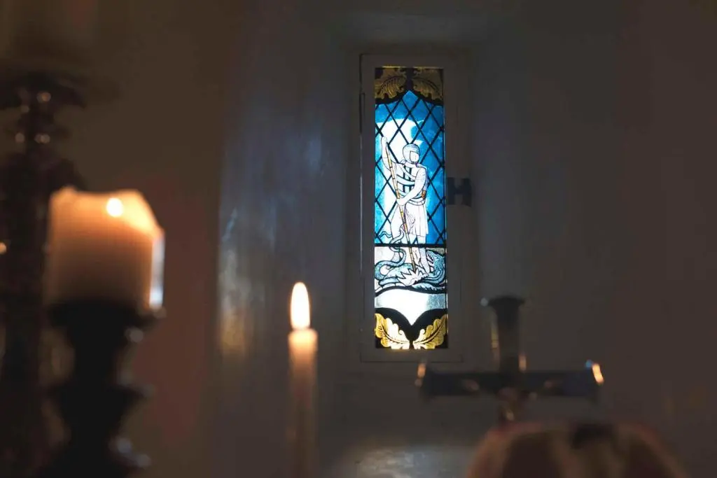 a stained glass window in a church with a candle at Forter Castle in Blairgowrie