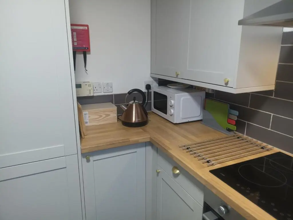 a kitchen with white cabinets and a tea kettle on a counter at Steam Train Cottage in Aviemore
