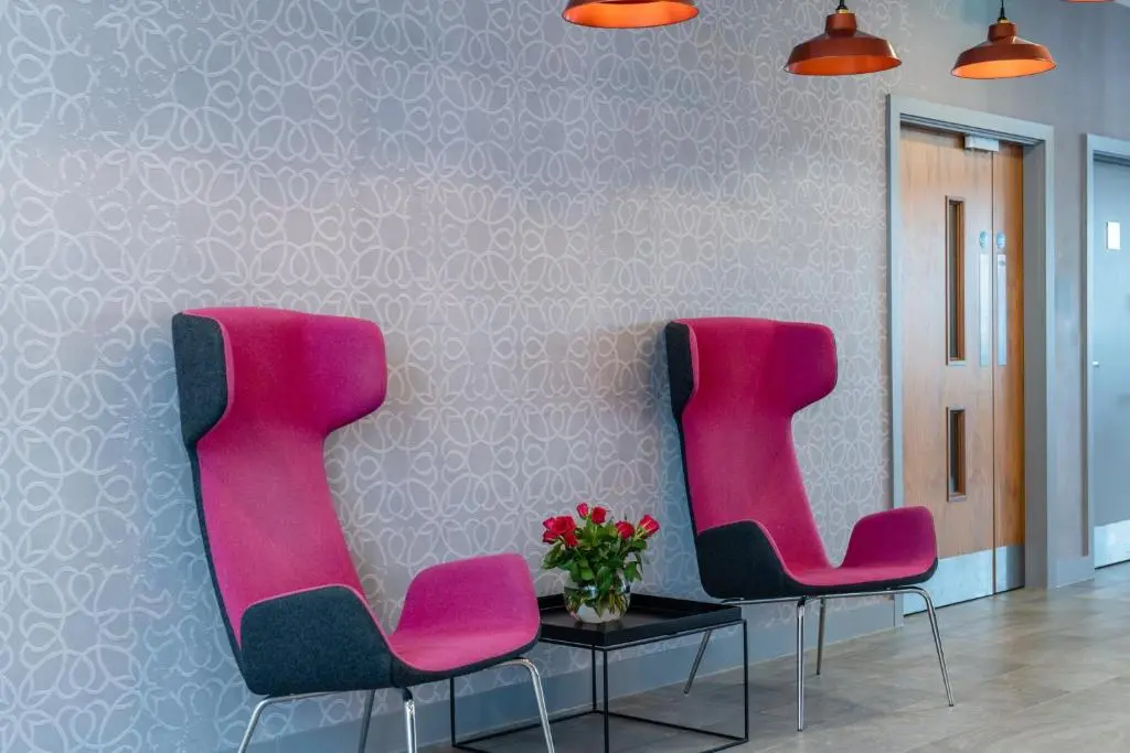 two pink chairs and a table in a room at Holiday Inn Express Aberdeen Airport by IHG in Dyce