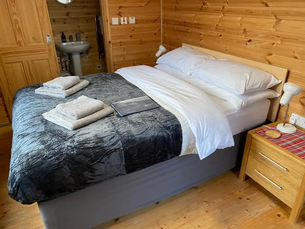 a bedroom with a bed with towels and a sink at An Cabar - Cabin in Aviemore, Cairngorms NP in Aviemore