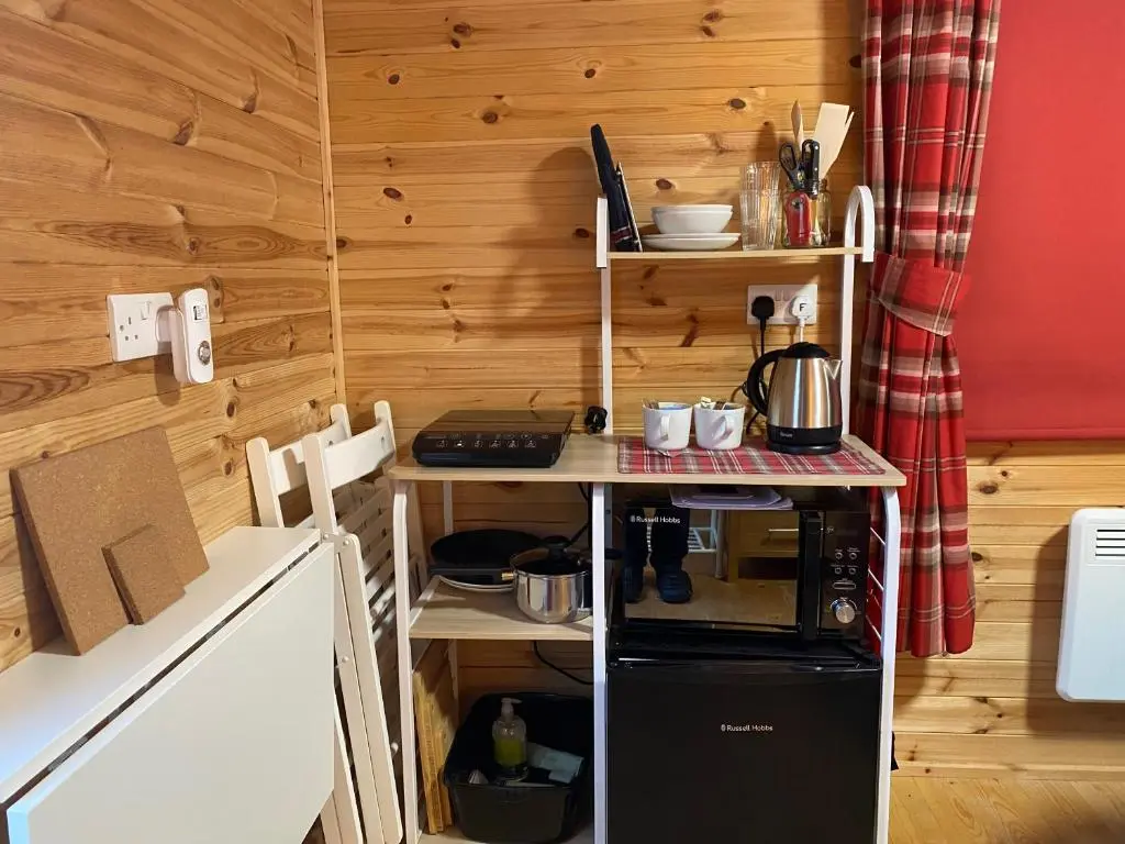 a small kitchen with a stove and a refrigerator at An Cabar - Cabin in Aviemore, Cairngorms NP in Aviemore