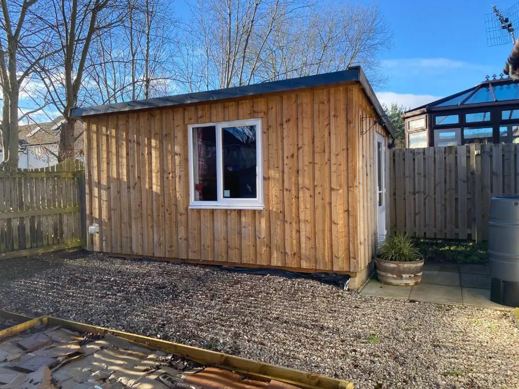 a wooden shed with a window in a yard at An Cabar - Cabin in Aviemore, Cairngorms NP in Aviemore