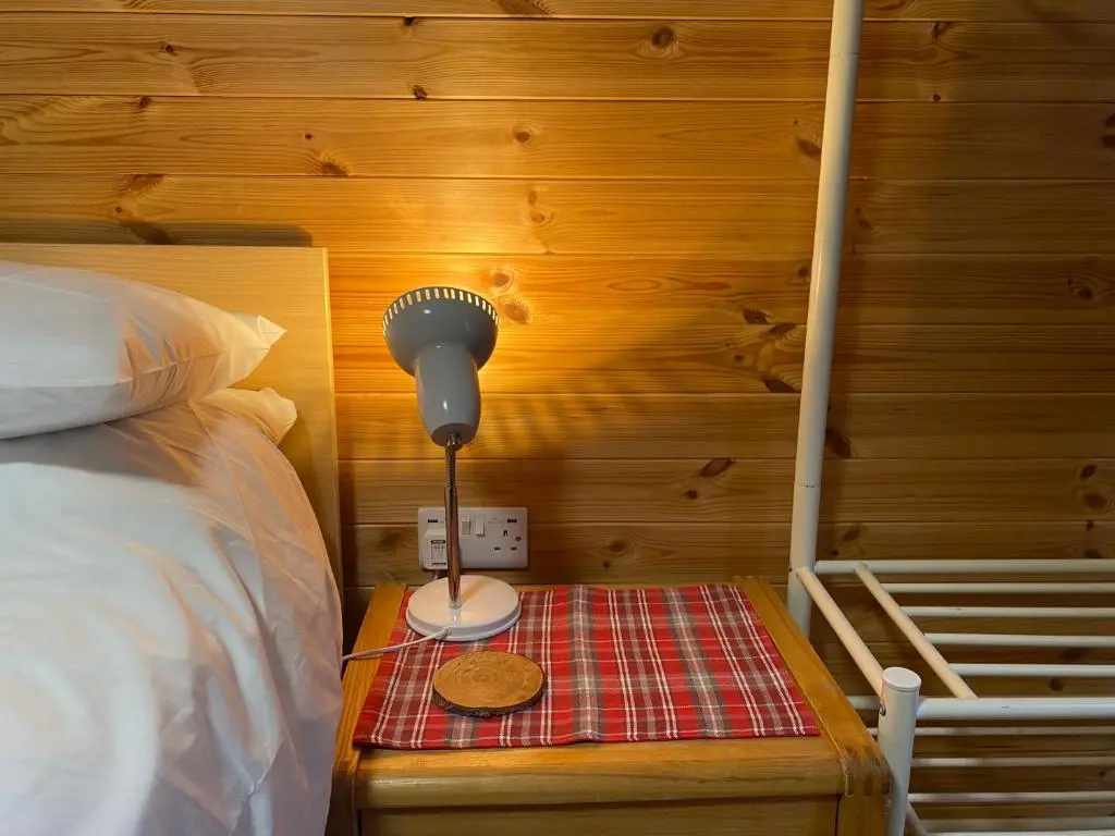 a lamp sitting on a table next to a bed at An Cabar - Cabin in Aviemore, Cairngorms NP in Aviemore